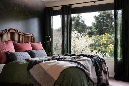 1 dormitorio con cama y ventana grande en Treehouse Spa Villa Daylesford, en Daylesford