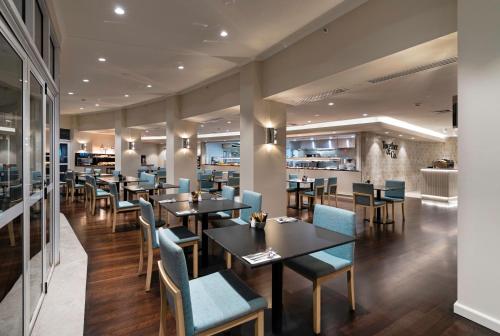 um restaurante com mesas e cadeiras e um bar em Hilton Garden Inn Darwin em Darwin