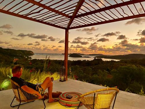 a man sitting on a porch watching the sunset at Lobster Bay Lombok in Awang