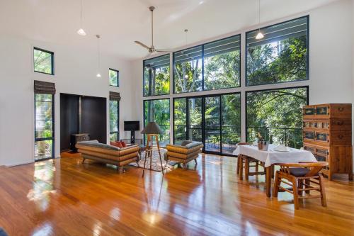 a living room with a table and chairs and large windows at Pethers Rainforest Retreat in Mount Tamborine