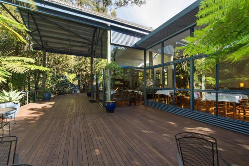 タンボリーン・マウンテンにあるPethers Rainforest Retreatのデッキ(椅子、テーブル付)が備わる建物