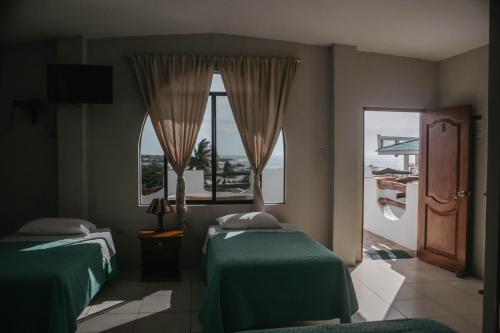 a bedroom with two beds and a large window at Casa de Nelly in Puerto Baquerizo Moreno