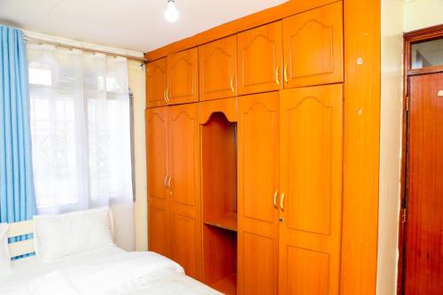 1 dormitorio con armarios de color naranja, 1 cama y ventana en SYLVIA'S LUXURIOUS APARTMENT, en Kisumu
