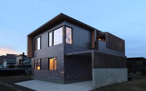 a house with a black roof and windows at Apres in Furano