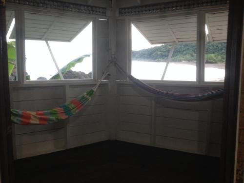 a hammock in a room with two windows at The Hill B&B (El Morro Hosteria) in El Valle