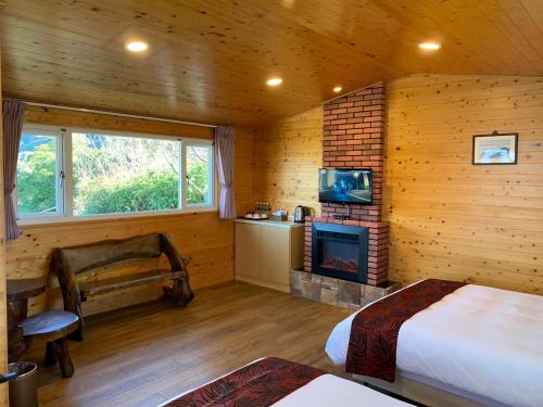 Dormitorio en cabaña de madera con cama y chimenea en Happy Farm Homestay, en Fuxing