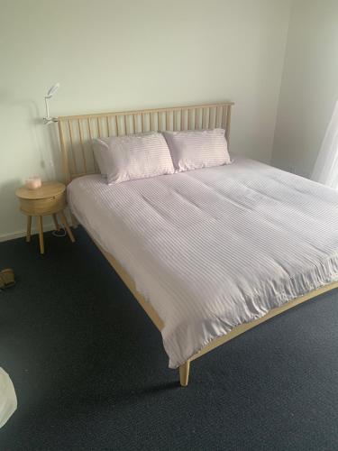a large bed in a bedroom with a night stand at The Golf House at St Andrews Beach in Fingal