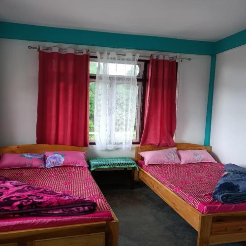 two beds in a room with red curtains at Mairung Gaon Farm Stay in Rishop