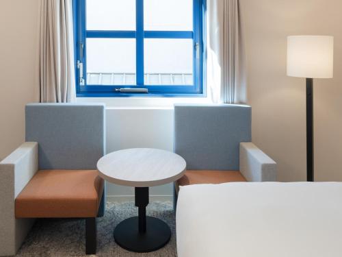 a room with a table and a chair and a window at Hotel Il Palazzo in Fukuoka