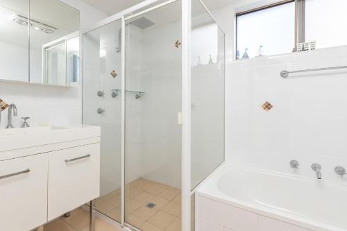 ein weißes Bad mit einer Dusche und einem Waschbecken in der Unterkunft Oceancrest 11 in Forster