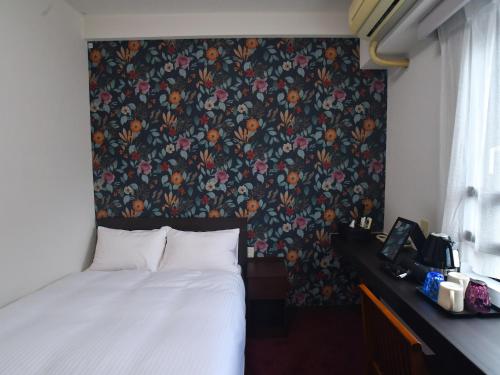 a bedroom with a bed and a floral wallpaper at ＦＯＲＢＥＬＬ　ＳＴＡＹ　ＹＵＲＩＧＡＯＫＡ in Ikuta