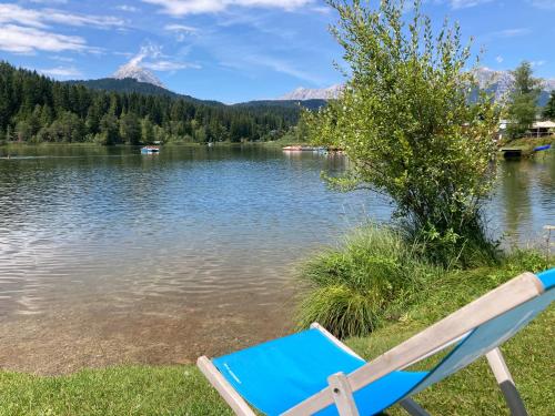 a blue chair sitting on the shore of a lake at RELAX Seefeld Apartman in Seefeld in Tirol