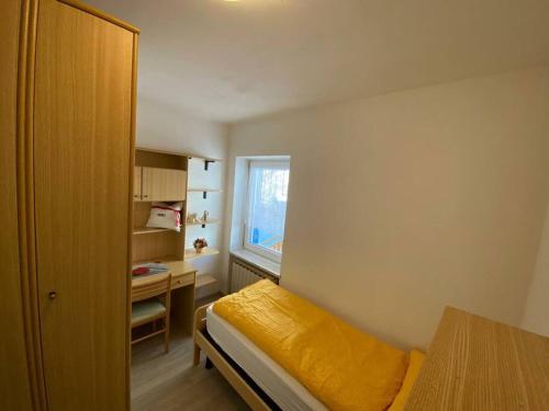 a bedroom with a bed and a desk and a window at Ciamorc Relax & Sport Appartament for max 2 Adults 1 child 1 infant in Canazei