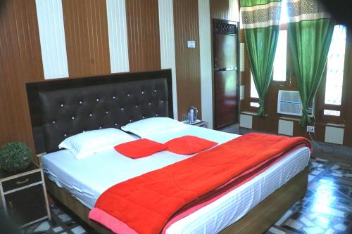 a bed with red pillows and a red blanket at Corbett Atulyam Home Stay in Rāmnagar