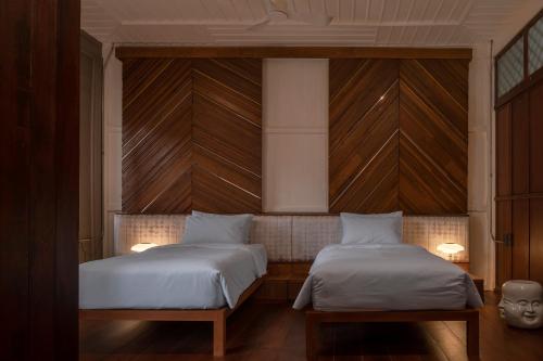 two beds in a room with wood paneled walls at neil niwas in Bangkok