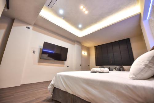 a bedroom with a large bed with a flat screen tv at Two Couples Leisure Art Motel in Tainan