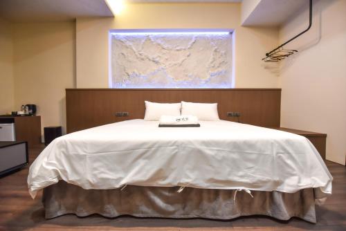 a large white bed in a room with a map on the wall at Two Couples Leisure Art Motel in Tainan