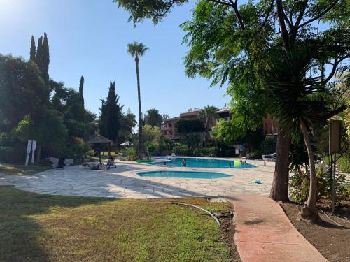 a swimming pool in a park with a palm tree at Paradise Gardens 3 - superb 1 bed apartment in Paphos
