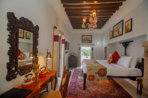 a bedroom with a bed and a desk and a mirror at Amritara Chandra Mahal Haveli, Bharatpur in Bharatpur