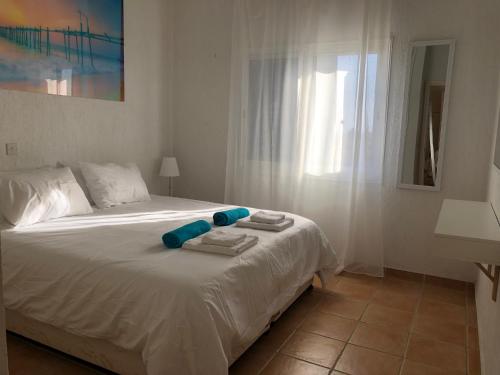 a bedroom with a white bed with towels on it at Limnaria Gardens - 1 bedroom, sunny apartment with stunning pool views in Paphos City