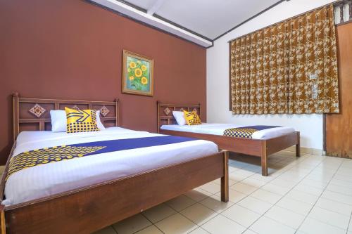 a bedroom with two beds and a window at SUPER OYO 1927 Hotel Candra Adigraha in Denpasar