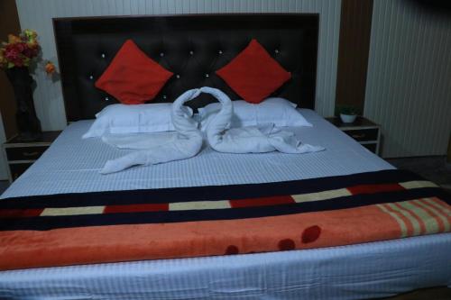 a bed with two white towels and red pillows at Corbett Atulyam Home Stay in Rāmnagar