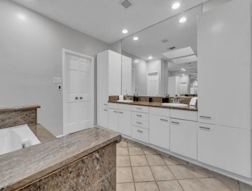a white kitchen with white cabinets and a marble counter top at LUX 4BR Home w/ Hot tub & Pool, 15 min to downtown in Houston