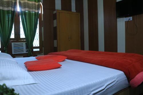 two beds with red pillows on them in a room at Corbett Atulyam Home Stay in Rāmnagar