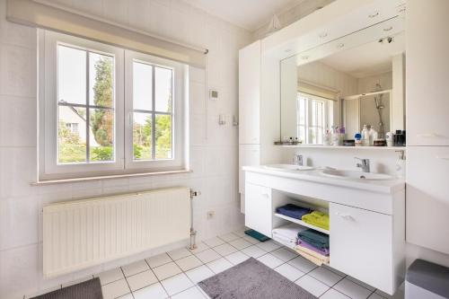 a white bathroom with a sink and a mirror at B&b La Villa Orchidées, breakfast included in Bassenge