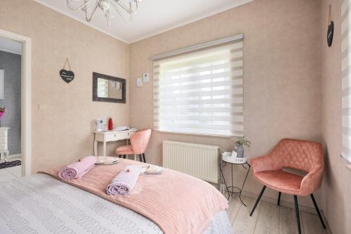 a bedroom with a bed and two pink chairs at B&b La Villa Orchidées, breakfast included in Bassenge