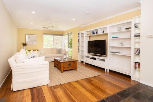 a living room with white furniture and a flat screen tv at Inglewood Gardens in Rosebud