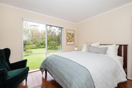 a white bedroom with a bed and a window at Inglewood Gardens in Rosebud