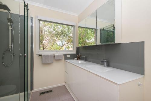 a bathroom with two sinks and a shower and a window at Inglewood Gardens in Rosebud
