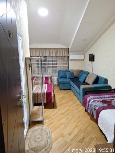 a living room with a blue couch and a bed at GUEST HOUSE 15A in Kutaisi