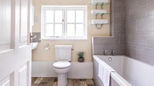 a bathroom with a toilet and a tub and a window at Trelawney Cottage - sleeps 8 - near Wadebridge in Saint Wenn