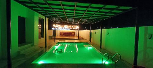 a swimming pool with green lights in a room at استراحة المرجان 