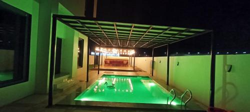 的住宿－استراحة المرجان，一座带绿色灯光的游泳池