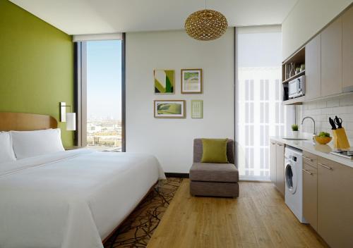 a bedroom with a large white bed and a kitchen at Element Me'aisam, Dubai in Dubai