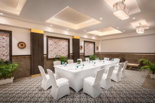a conference room with a large white table and white chairs at Palasa Hotel in Muzaffarnagar