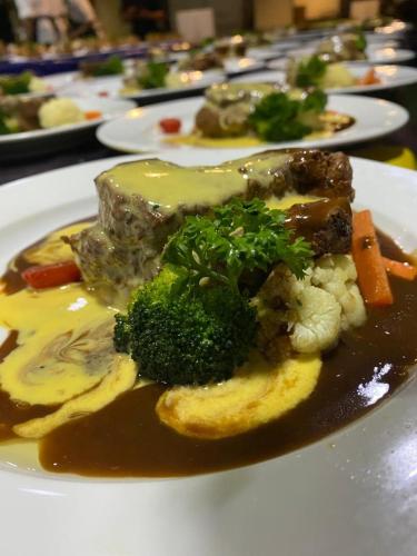 a plate of food with broccoli and meat and gravy at Park Avenue Hotel Sungai Petani in Sungai Petani