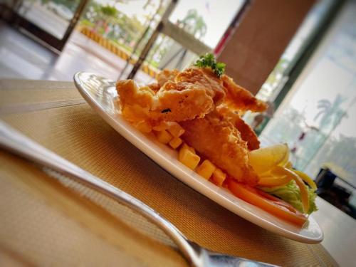 a plate of food with fish and vegetables on a table at Park Avenue Hotel Sungai Petani in Sungai Petani