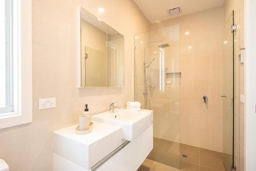 a white bathroom with a sink and a shower at The Royal Apartment in Mornington in Mornington
