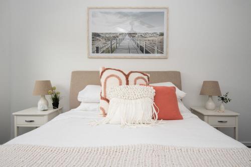 a bedroom with a white bed with orange and white pillows at Waterfall Gully Retreat with Gas heated Pool in Rosebud