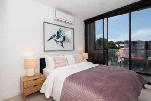 a bedroom with a bed and a large window at Bayside living at The Hampton in Melbourne