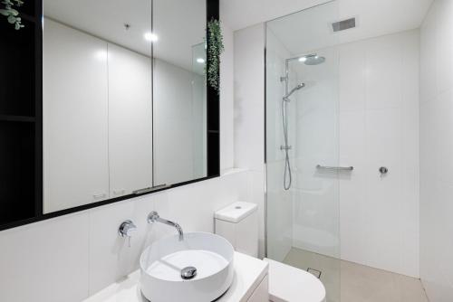 a white bathroom with a sink and a shower at Bayside living at The Hampton in Melbourne