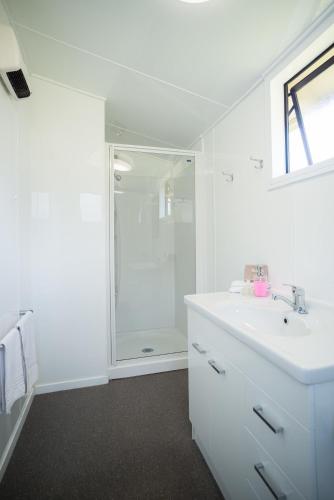 a white bathroom with a shower and a sink at Fox Glacier TOP 10 Holiday Park & Motels in Fox Glacier