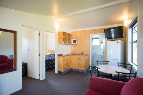 a room with a table and a kitchen and a bed at Fox Glacier TOP 10 Holiday Park & Motels in Fox Glacier