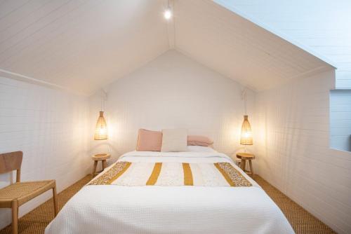 ein weißes Schlafzimmer mit einem Bett und zwei Leuchten in der Unterkunft Modern Haven in Vibey Fitzroy Walk to shops in Melbourne