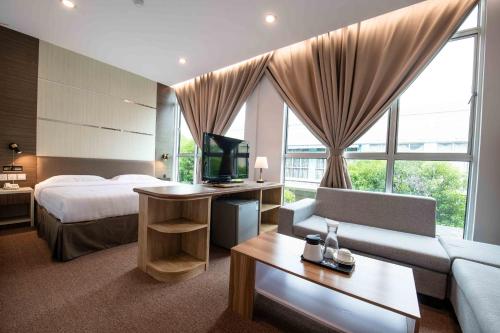 a hotel room with a bed and a couch and a tv at Hotel Meliden in Sandakan