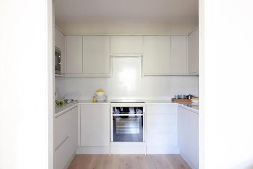 a white kitchen with white cabinets and an oven at Gulaid House Knightsbridge by Bob W London in London